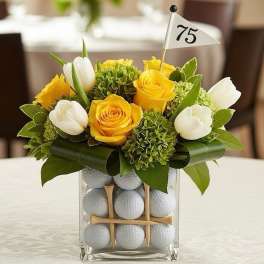 Yellow roses and white tulips in a glass vase filled with golf balls