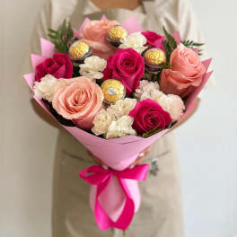 Bouquet of pink and peach roses with white carnations and gold-wrapped chocolates