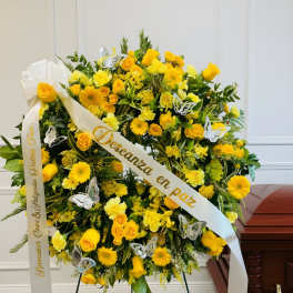 Yellow floral funeral wreath with white ribbon and butterfly accents