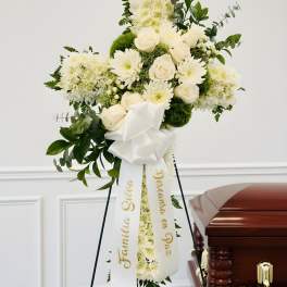 White funeral spray on an easel beside a casket
