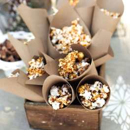 Paper cones of caramel popcorn arranged in a wooden crate