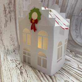 White paper house-shaped gift box with a holiday wreath decoration