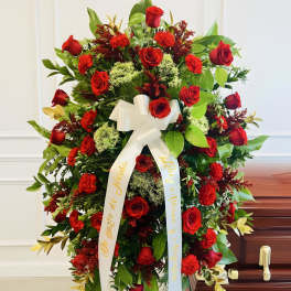 Large red rose funeral spray with white ribbon on an easel