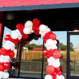 Red and white balloon arch outside a Guthrie's Chicken Fingers storefront