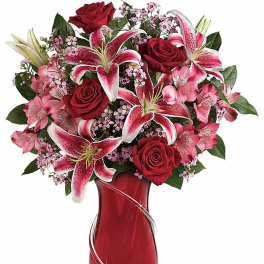 Red roses and pink lilies arranged in a red glass vase with silver swirl accents