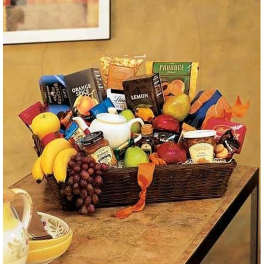 Large wicker gift basket filled with assorted gourmet snacks and fresh fruit on a table