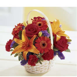 White handled basket of red roses, orange lilies, red gerberas, and purple filler flowers