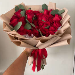 Bouquet of red roses wrapped in beige paper with a red ribbon