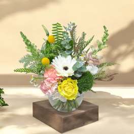 Mixed flower arrangement in a clear glass vase with white, yellow, and pink blooms