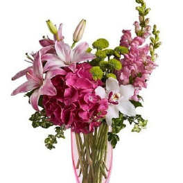 Tall pink and white arrangement with lilies, hydrangea, orchids and mums in a pink glass vase