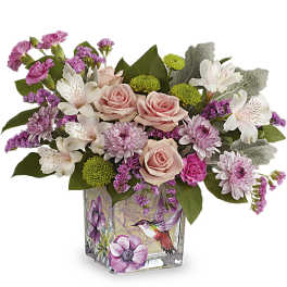 Pink roses, white alstroemeria, and purple mums in a square glass vase with a hummingbird design