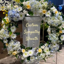 Large sympathy wreath with white, blue, and yellow flowers