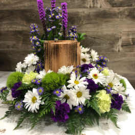White daisies and purple flowers arranged around a copper vase