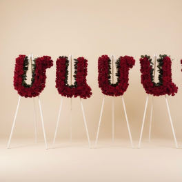 Four red floral letter arrangements on white easels