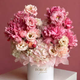 Pink and white floral arrangement in a white hat box