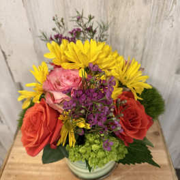 Mixed bouquet of roses, yellow daisies, and purple filler flowers in a vase