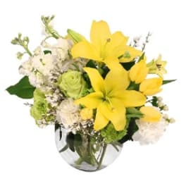 Yellow lilies and white flowers in a clear glass vase