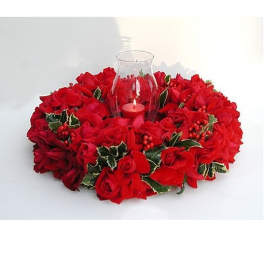 Round wreath of red roses with holly and a glass candle holder in the center