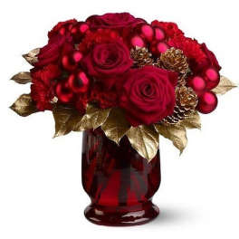 Red roses and carnations with red ornaments and gold leaves in a red glass vase