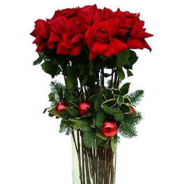 Tall arrangement of red roses with evergreen and red ornaments in a clear glass vase