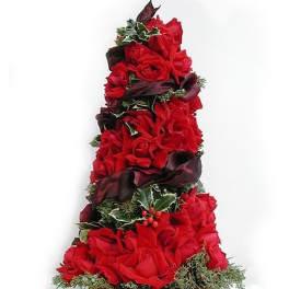 Tall cone-shaped arrangement of red roses with dark ribbon, holly, and evergreens in a shallow dish