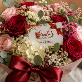 Bouquet of red and blush roses with white filler flowers and a gift card