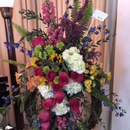 Tall floral standing spray with pink, white, yellow, and blue flowers