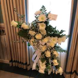 White floral standing spray on an easel with ribbon accents