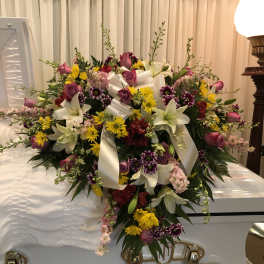 Large floral spray on a white casket with lilies and roses