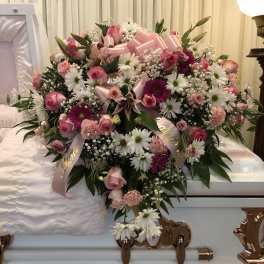 Pink and white funeral spray on a white casket
