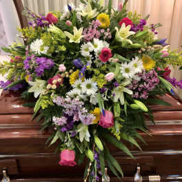 Large mixed floral spray on a casket with white lilies and pink roses