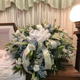 Large white funeral spray with lilies and roses on a casket