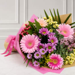 Bouquet of pink and purple daisies wrapped in brown paper and pink tissue