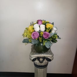 Bouquet of purple, white, and yellow roses in a dark vase