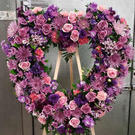 Heart-shaped floral wreath on a standing easel with pink and purple flowers