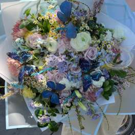 Large pastel bouquet with butterflies and mixed blooms wrapped in pale blue paper