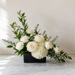 White roses and carnations arranged in a black rectangular vase