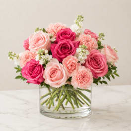 Pink and peach roses with carnations in a clear glass vase