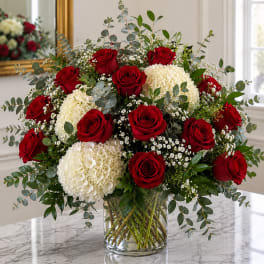 Red roses and white hydrangeas in a clear glass vase