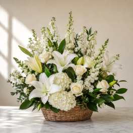White lilies and roses arranged in a wicker basket