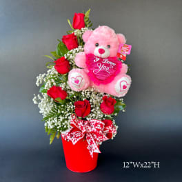 Pink teddy bear with red roses in a red container