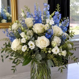 White roses and blue delphinium in a clear glass vase