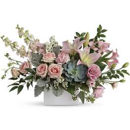Low pastel arrangement of pink roses, lilies, and a succulent in a white rectangular vase