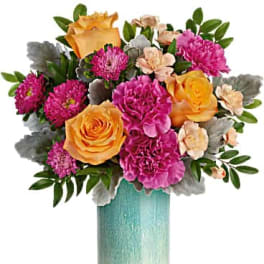 Bouquet of pink and orange flowers in a tall turquoise vase