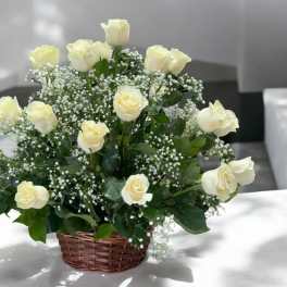 Cream roses arranged in a wicker basket with baby's breath