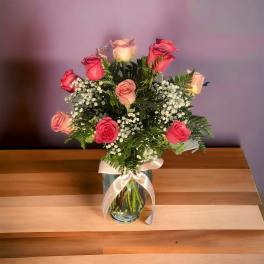Bouquet of pink and peach roses in a glass vase with a ribbon