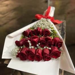 Bouquet of red roses wrapped in white paper with a red ribbon