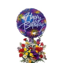 Birthday balloon above a colorful mixed flower arrangement in a blue vase