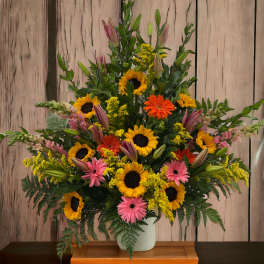 Tall mixed bouquet with sunflowers, pink gerberas, and yellow filler in a vase