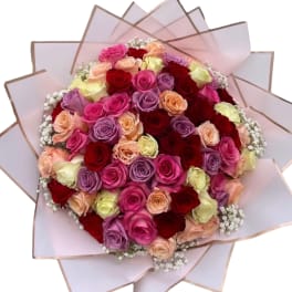 Round bouquet of multicolored roses wrapped in pale pink paper